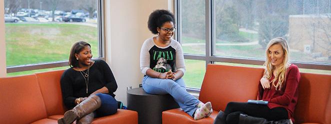 Students smiling on sofa in Mashburn Hall